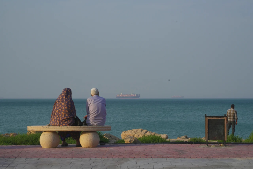 People sit at the shoreline as boats navigate the Strait of Hormuz on Qeshm Island, Iran, on April 28, 2026./source Getty Images|  Imperium Times | www. https://imperiumtimes.com | @imperiumtimesofficial
